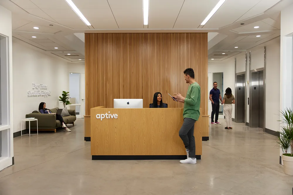a man standing at the Aptive office's reception, talking to his colleagues