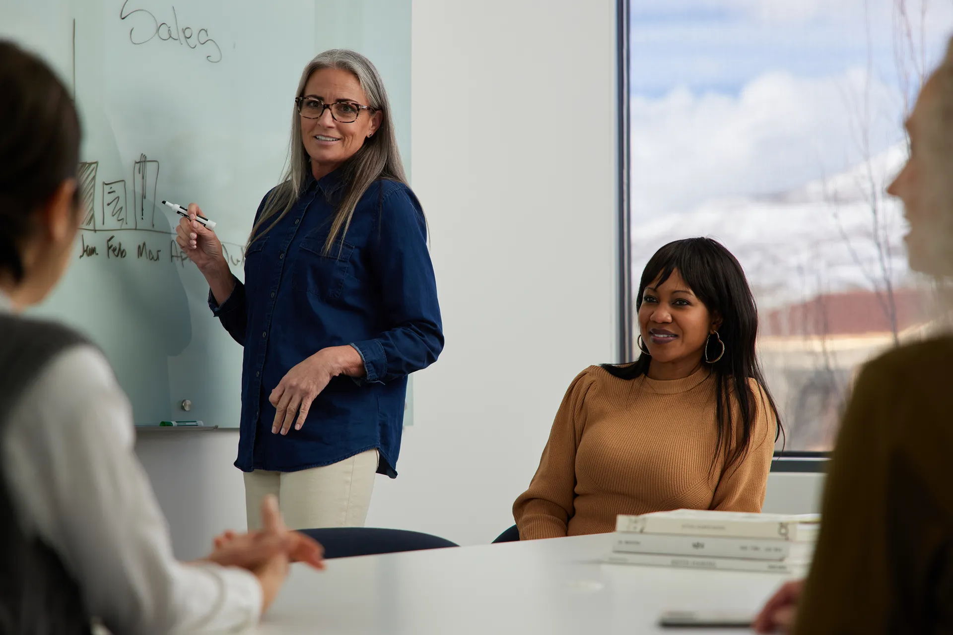 A diverse group of four smiling professionals collaborating together in a modern, bright office space