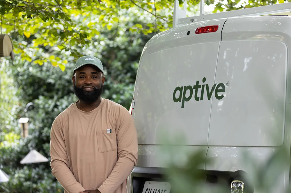 a man standing beside a van with the Aptive logo on it