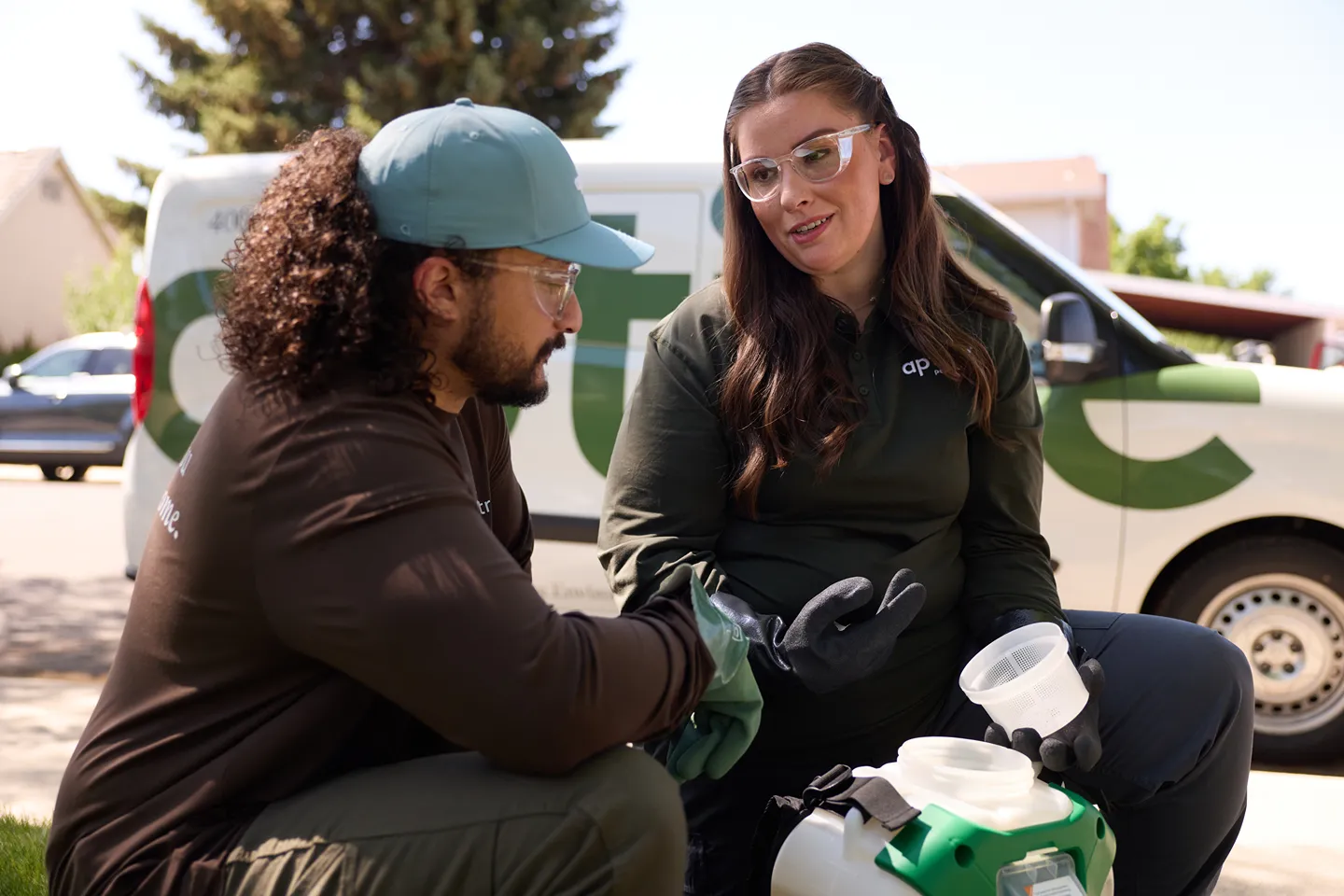 Two Aptive Environmental service professionals discussing while preparing equipment outdoors next to a company van