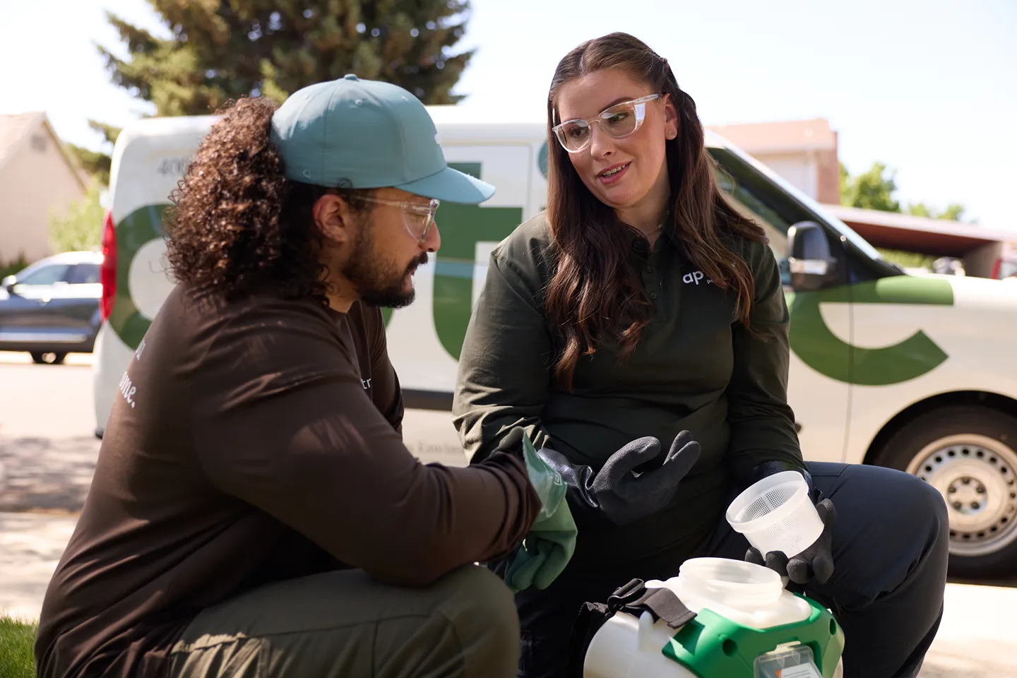Two pest control professionals in uniform are preparing a solution together.