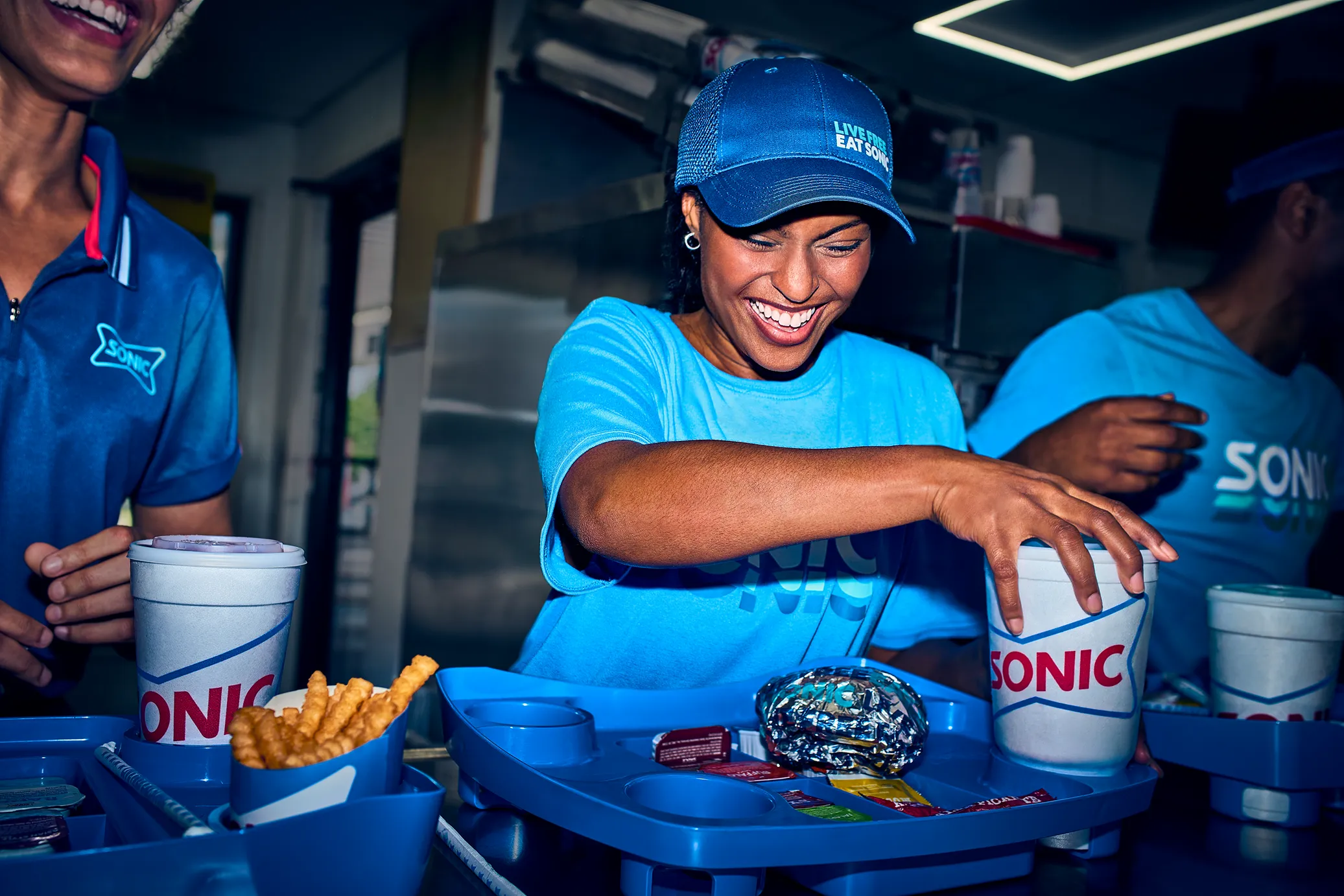 Sonic employee holding a tray with drinks and a bag, smiling