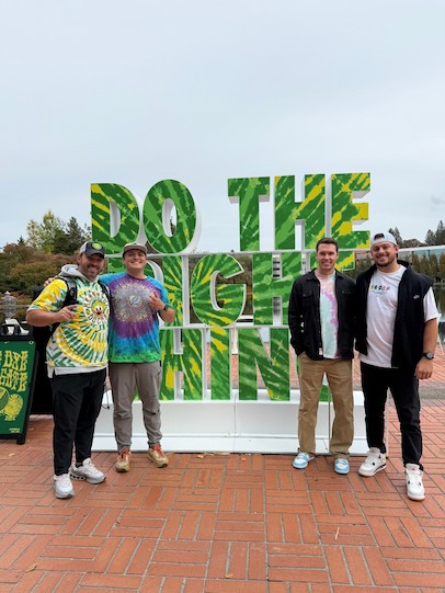 四名男子在大型3D藝術裝置前擺姿勢微笑。