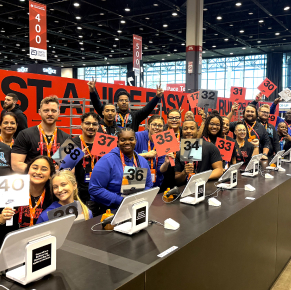 一大群熱情洋溢的活動工作人員在一長排收銀台後合照。