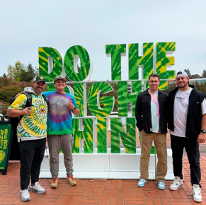 四名男子在大型3D藝術裝置前擺姿勢微笑。