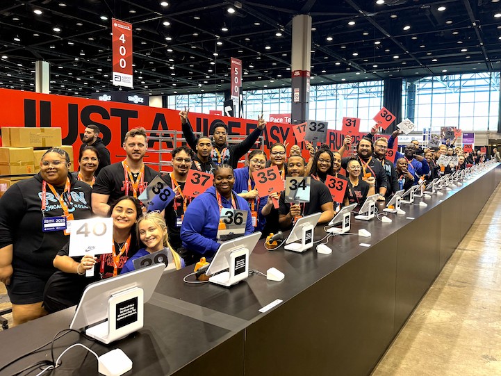 一大群熱情洋溢的活動工作人員在一長排收銀台後合照。