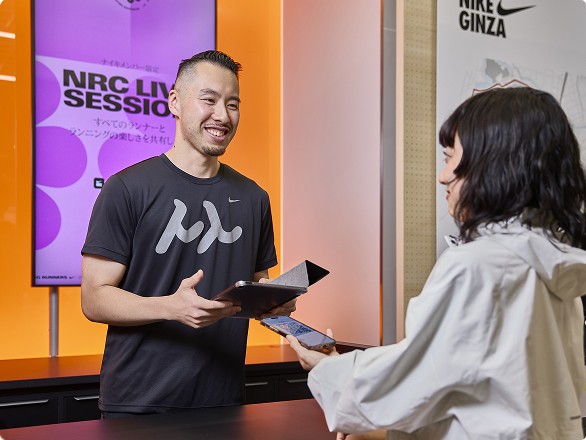 A man and woman interacting over a counter with a digital screen in the background