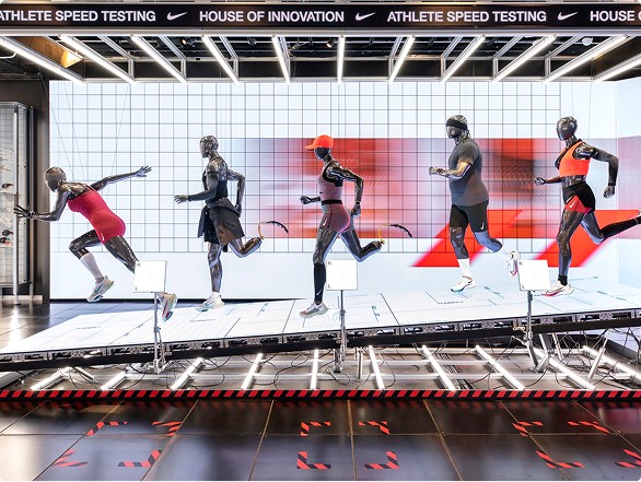 Mannequins dressed in athletic gear posed as if running on a treadmill with a grid and red-themed backdrop