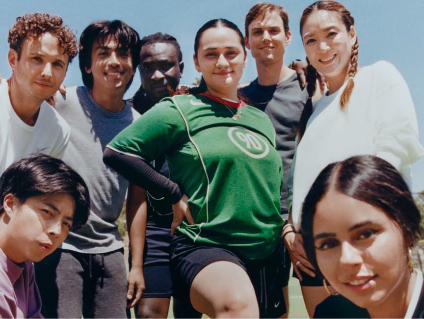 A group of eight people gathered outdoors, some smiling, holding a soccer ball