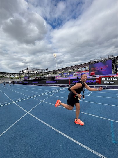Personne souriante sur une piste de course bleue lors d'un événement dans un stade