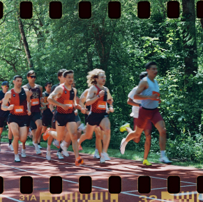 Un groupe de coureurs sur une piste rouge entourée d'arbres verts, avec une bordure de bande de film