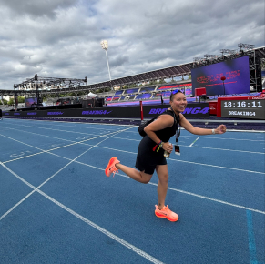Personne souriante sur une piste de course bleue lors d'un événement dans un stade