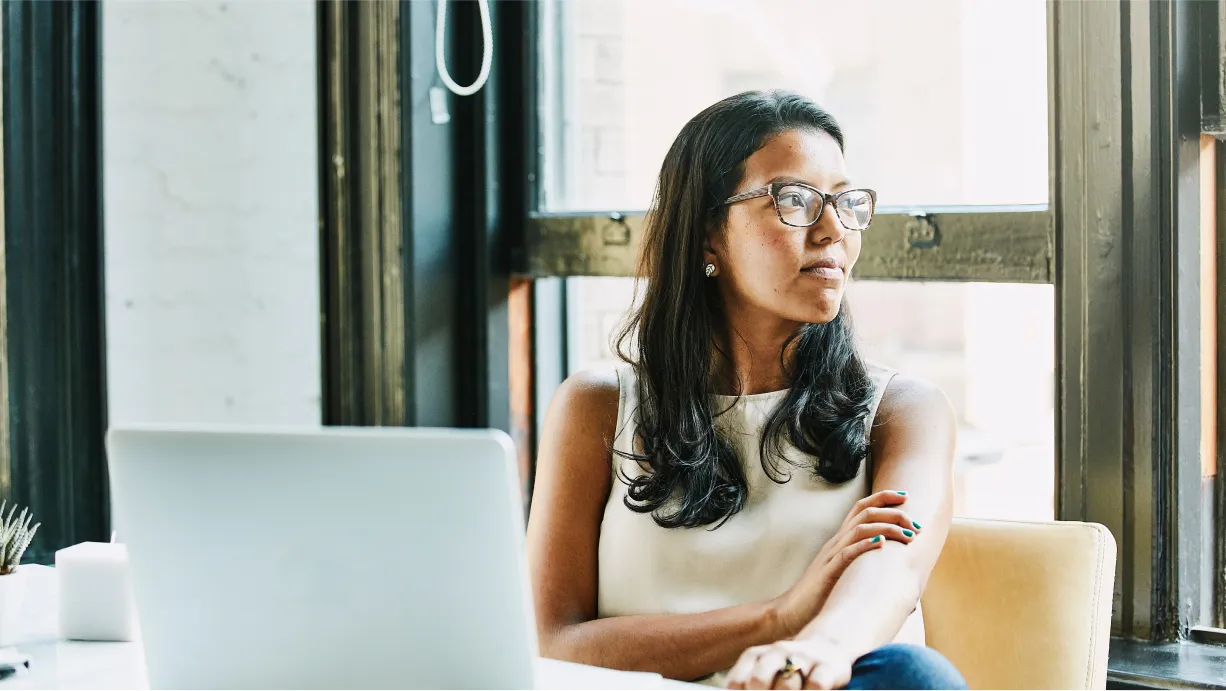 A woman sitting beside the window, working on her laptop
