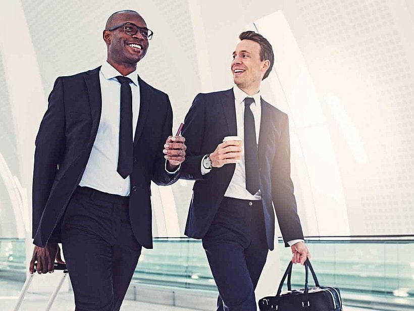 2 man in suits smiling at each other