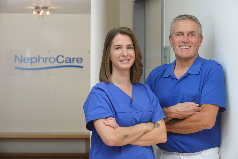 Male and female nurses are posing for a photo with their arms crossed.
