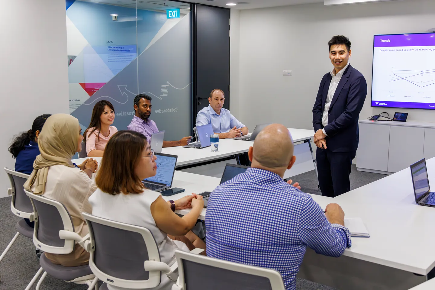 Corporate team member presenting trends data to a diverse group of colleagues in a modern conference room
