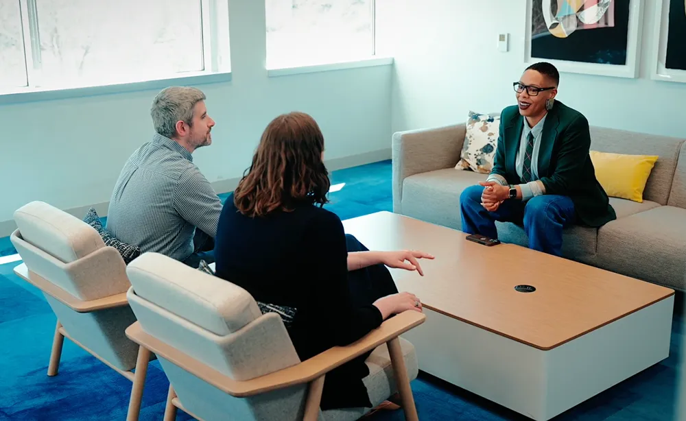 3 people sitting at a desk discussing something