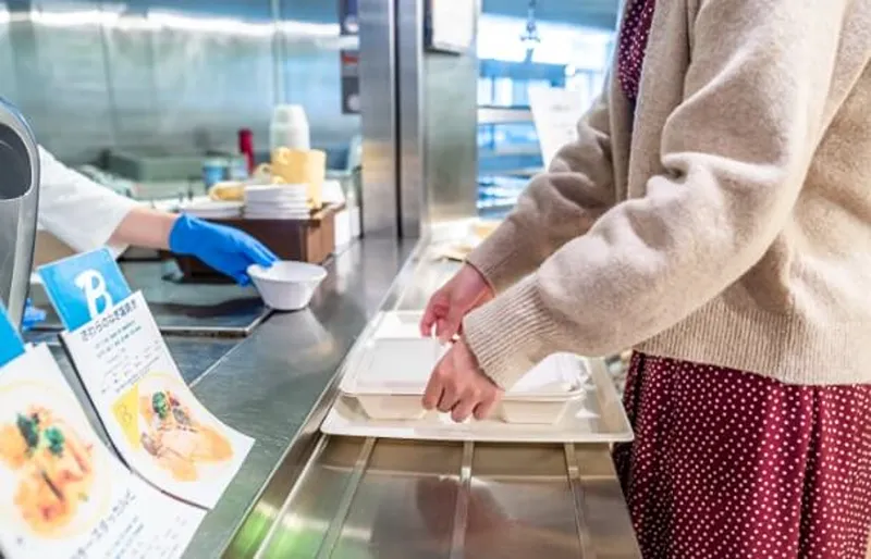 a woman taking dish in a canteen