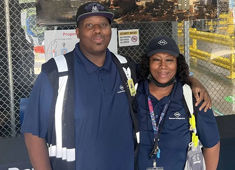Two workers are taking a photo with their arms around each other.