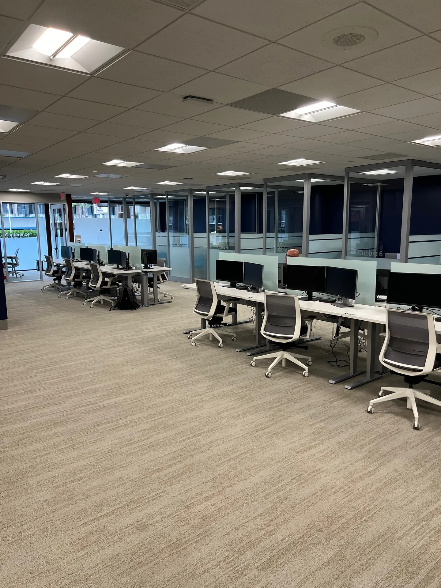 An empty, modern open-plan office space with rows of desks, chairs, and computers