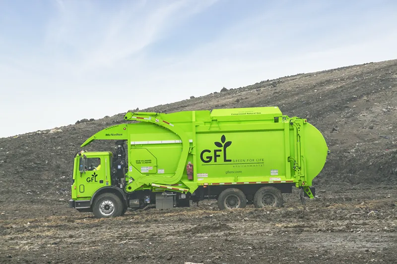 Bright green garbage truck at a landfill, labeled GFL Green for Life