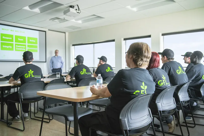 Employees in a training session listen attentively to a presenter, demonstrating commitment to their company