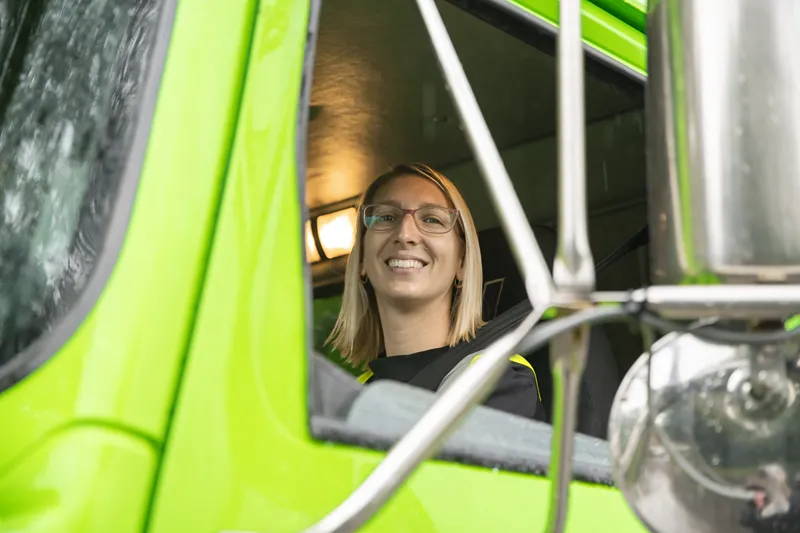 Smiling woman sitting in the cab of a bright green truck