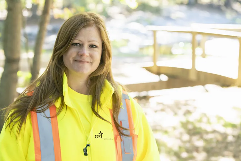 Woman in a yellow safety vest smiling outdoors