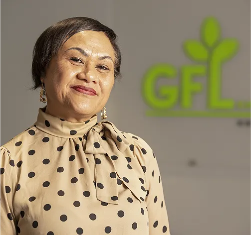 Portrait d'une femme en blouse beige à pois devant un logo GFL.