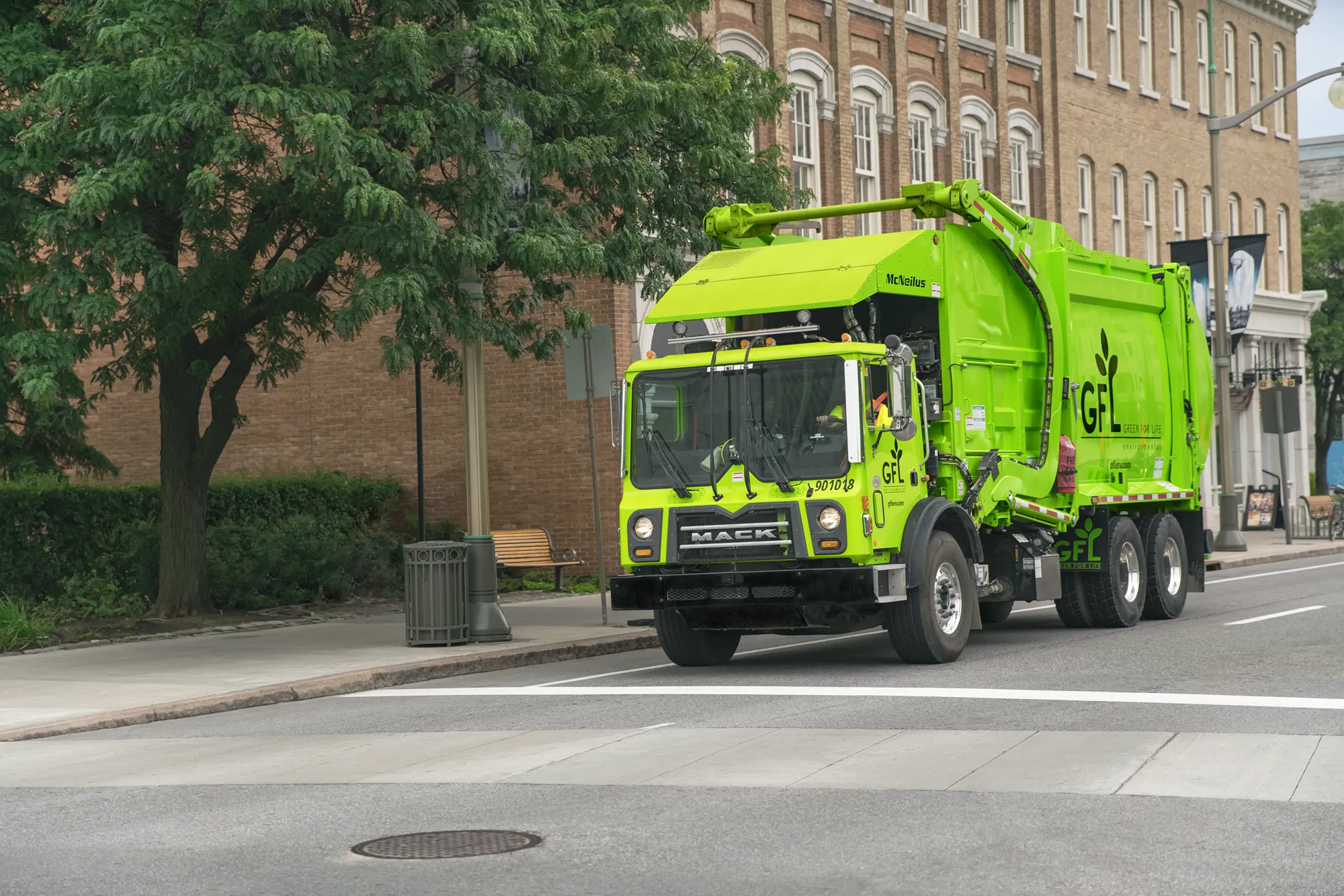 Bright green garbage truck driving down a city street