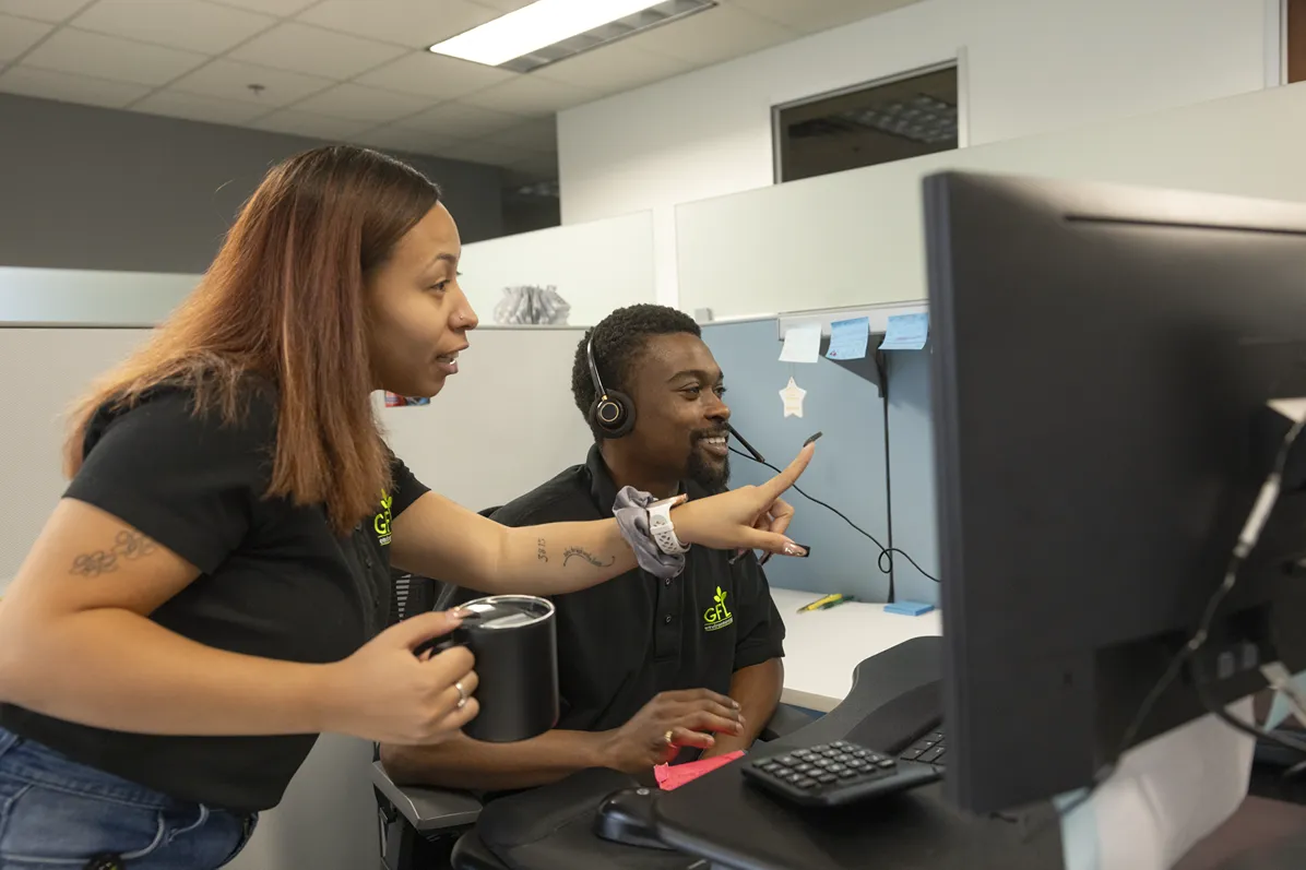 Two colleagues collaborate at a computer in a professional office setting