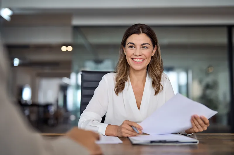 Une femme examinant des documents RH à une table.