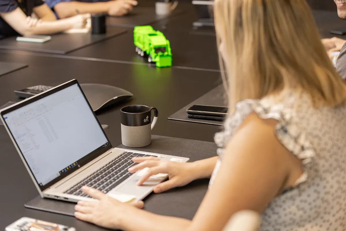 Des collègues souriants collaborant sur un ordinateur portable, échangeant des idées.