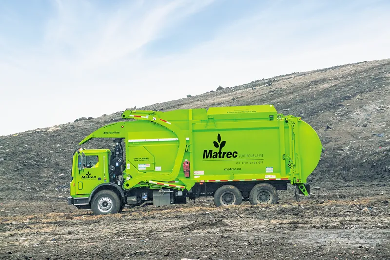 Camion poubelle vert vif dans une décharge, portant l'inscription GFL Green for Life.