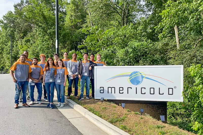 Group of people standing in front of Americold sign on sunny day