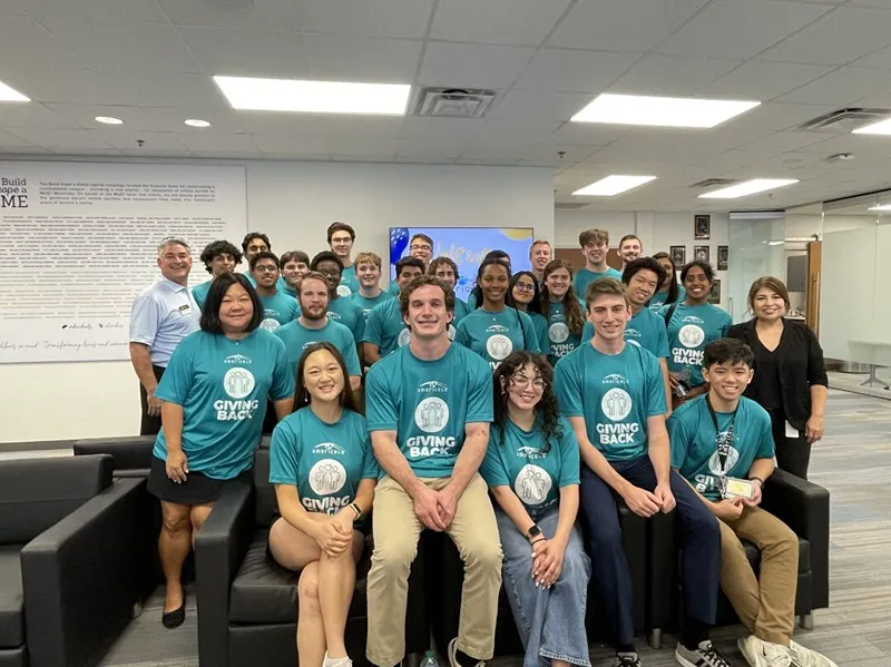 Group of people in teal shirts posing together indoors.