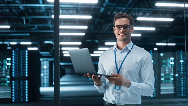 Man with laptop working in server room with cables and equipment