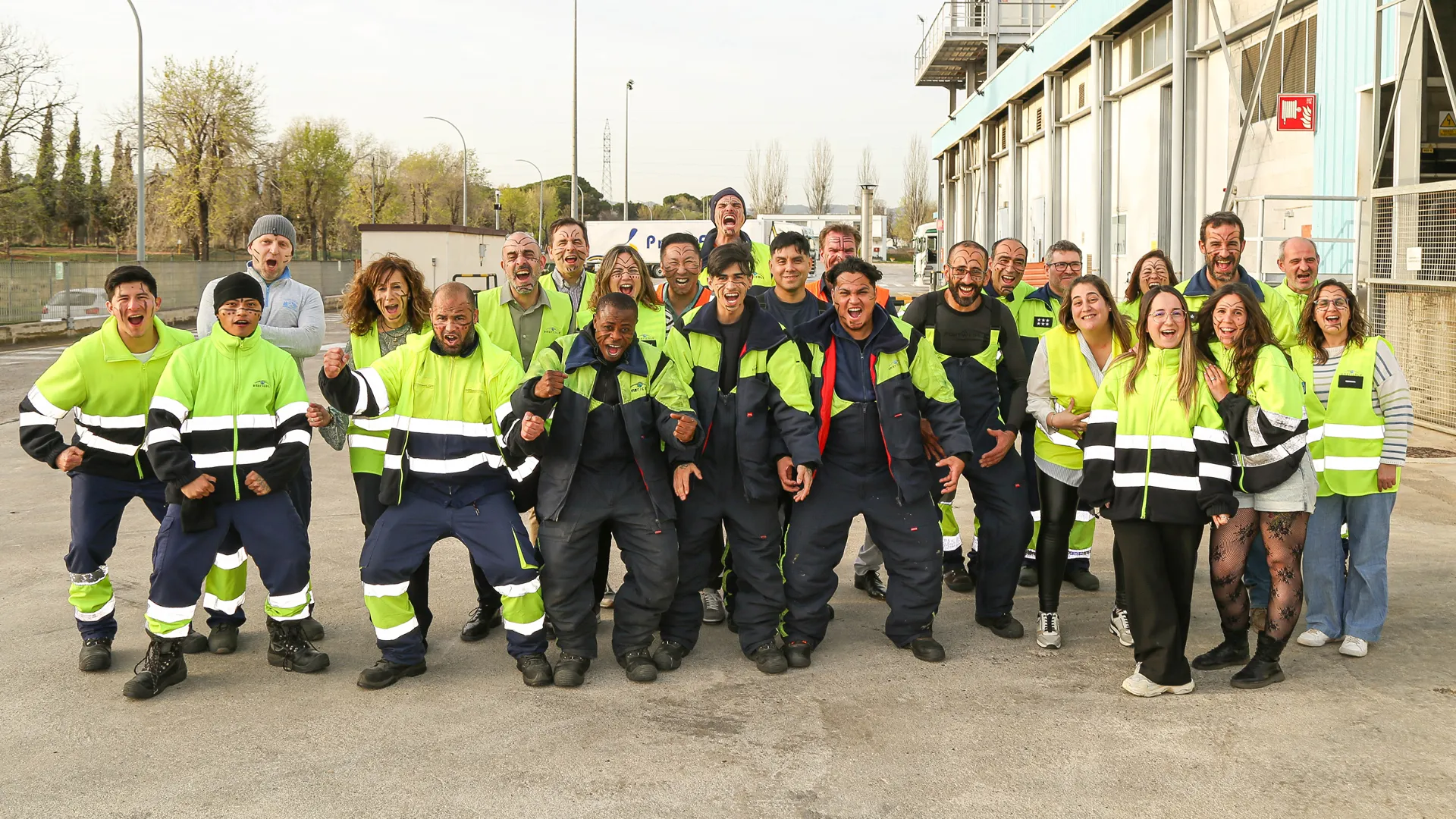 Group of workers in safety gear posing outside industrial facility