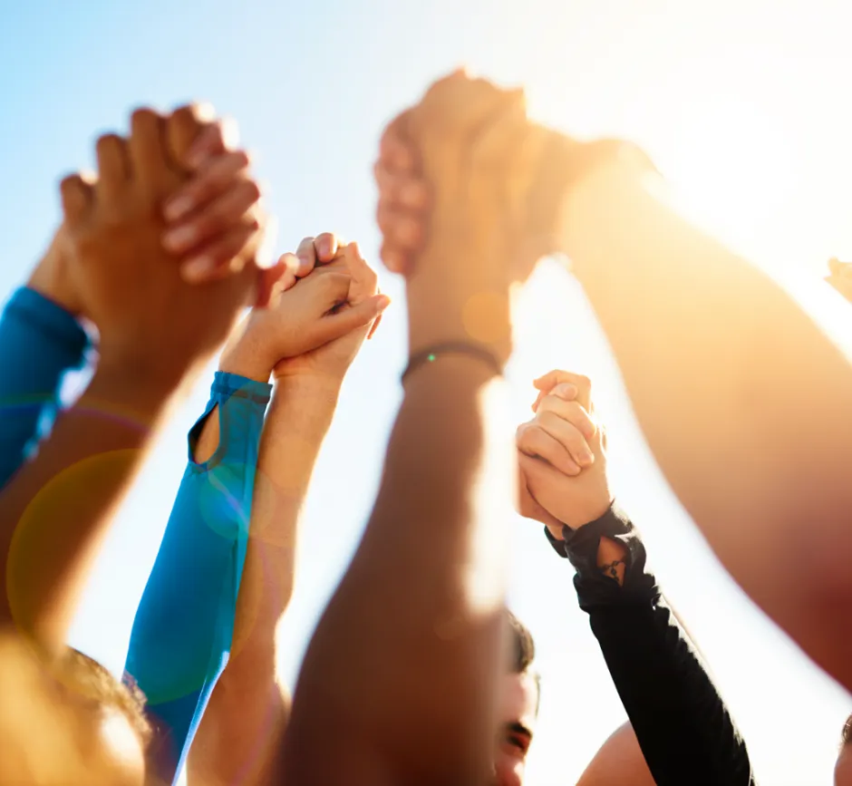 Hands interlocked and raised against a sunny sky