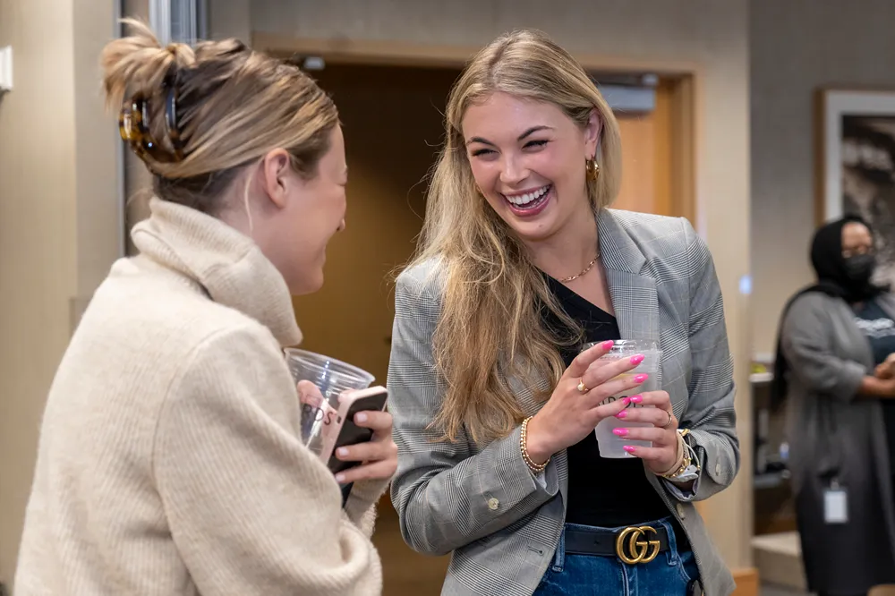 two women talking and laughing in a hallway