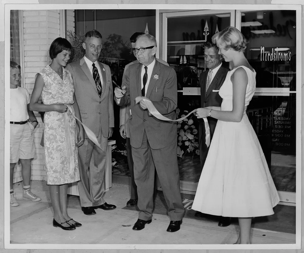 a group of people cutting a ribbon at a store
