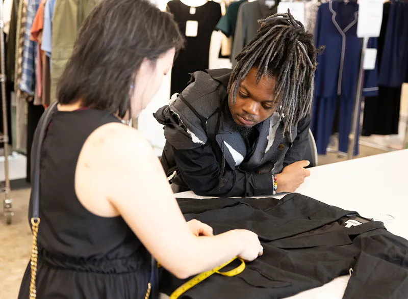 a woman is measuring a black jacket in a clothing store