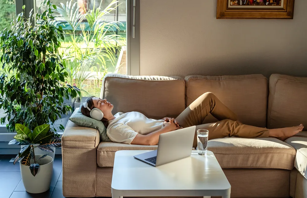 a woman is laying on a couch with headphones on