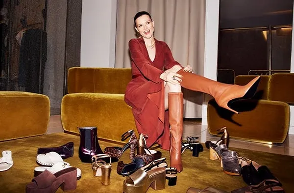 a woman sitting on a couch surrounded by shoes