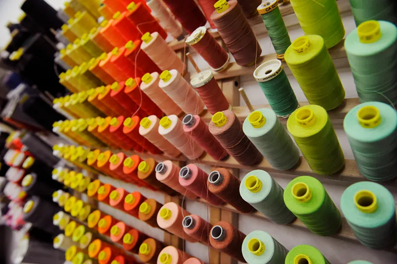 Rows of colorful spools of thread on a rack
