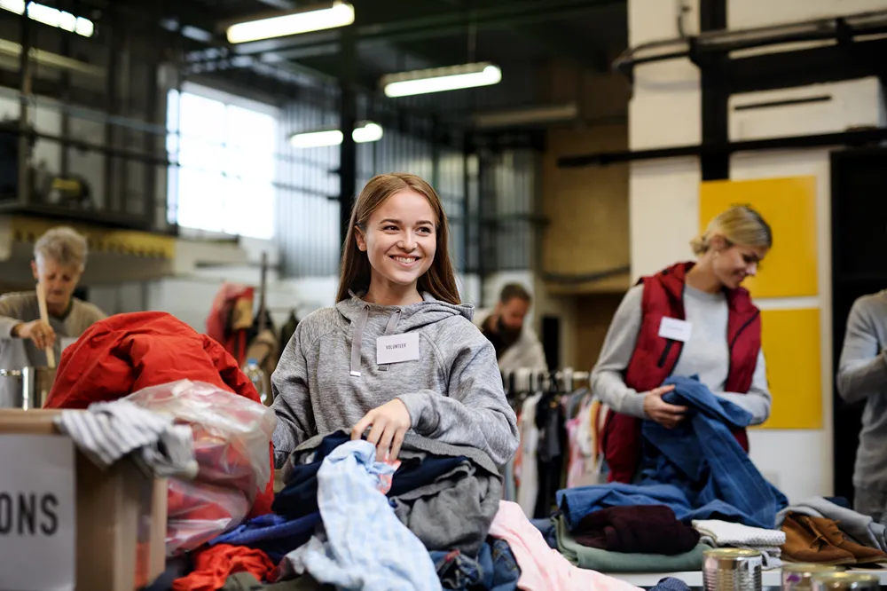 a woman smiles while holding a pile of clothes