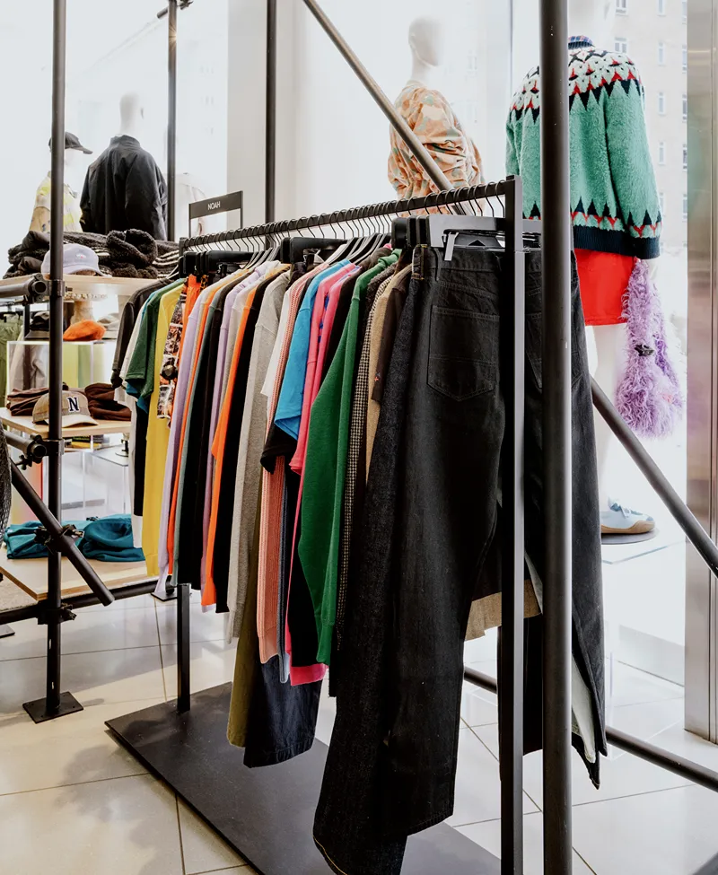 clothing rack in a clothing store with clothes on it