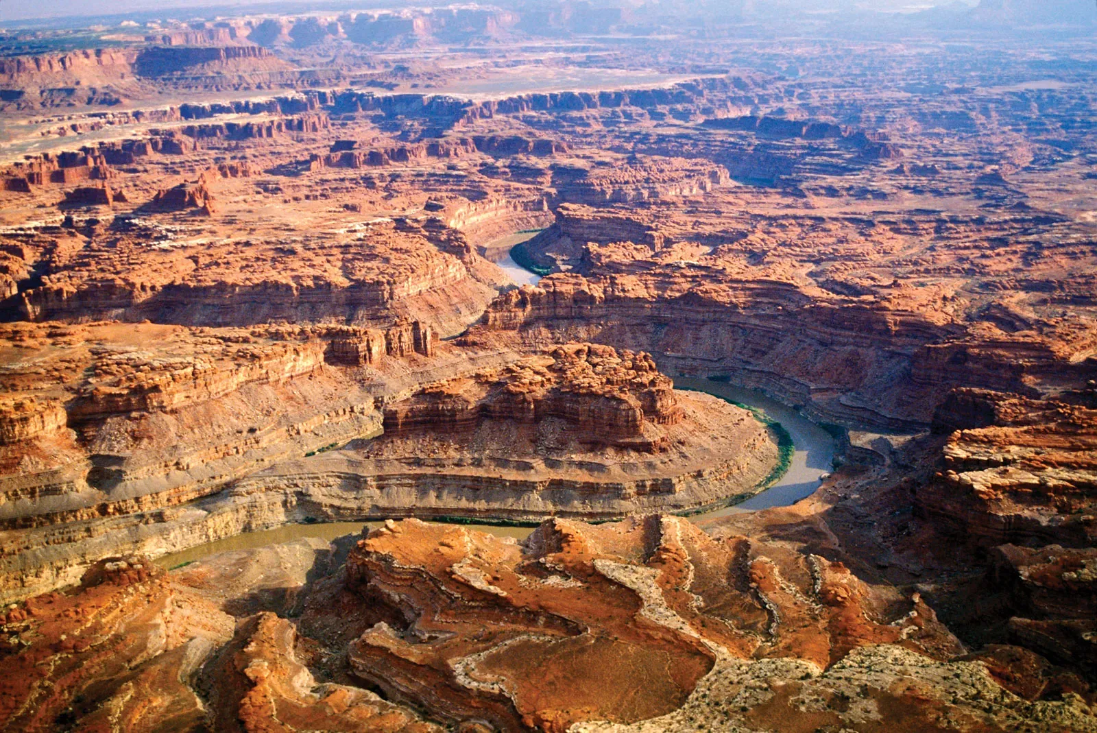 Aerial view of a winding river through rugged canyon terrain with layered rock formations