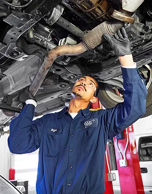 Mechanic working under car in garage with tools