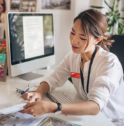 Woman working at desk with computer and documents in office setting